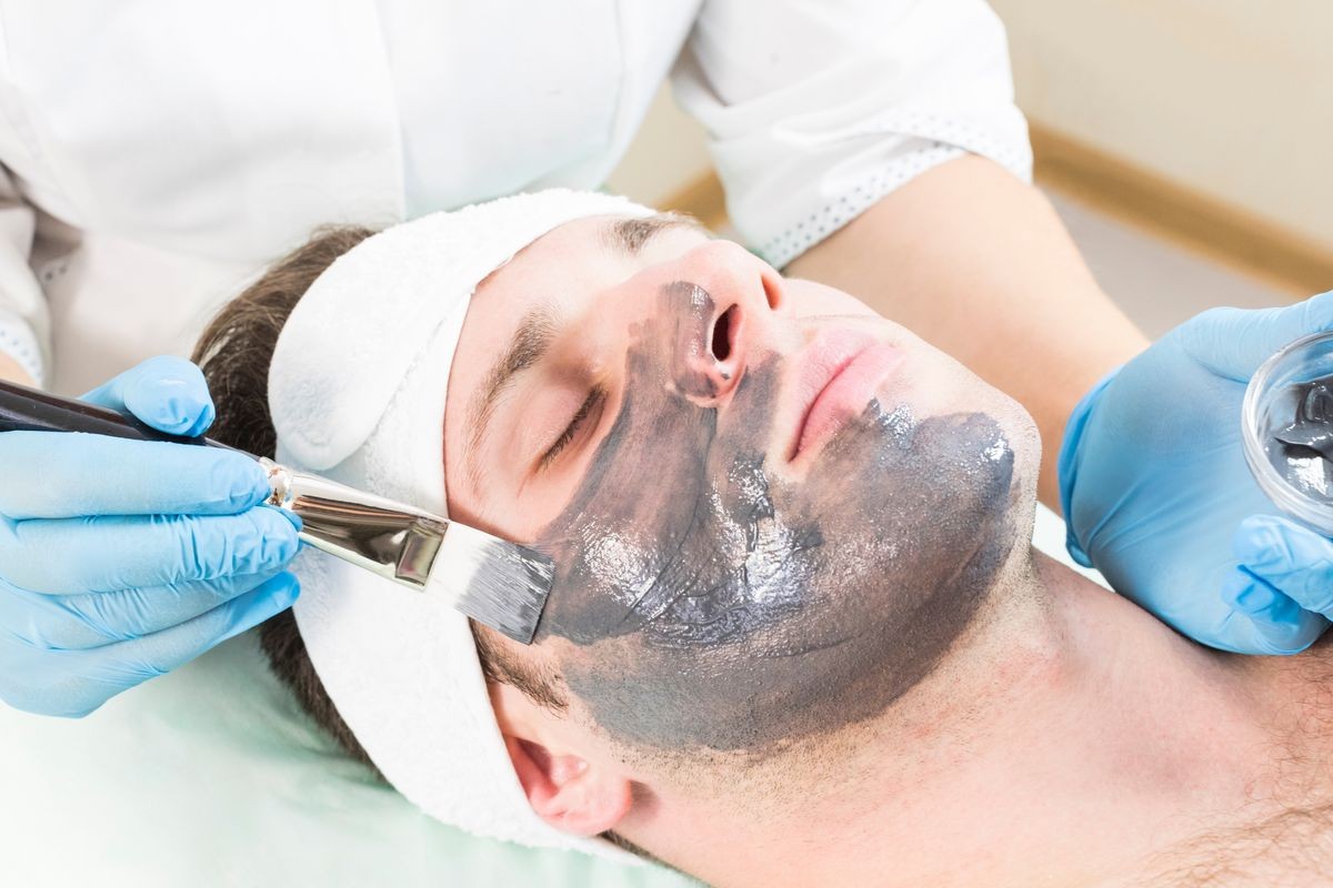 A young man is undergoing a mask treatment in a beauty salon spa.